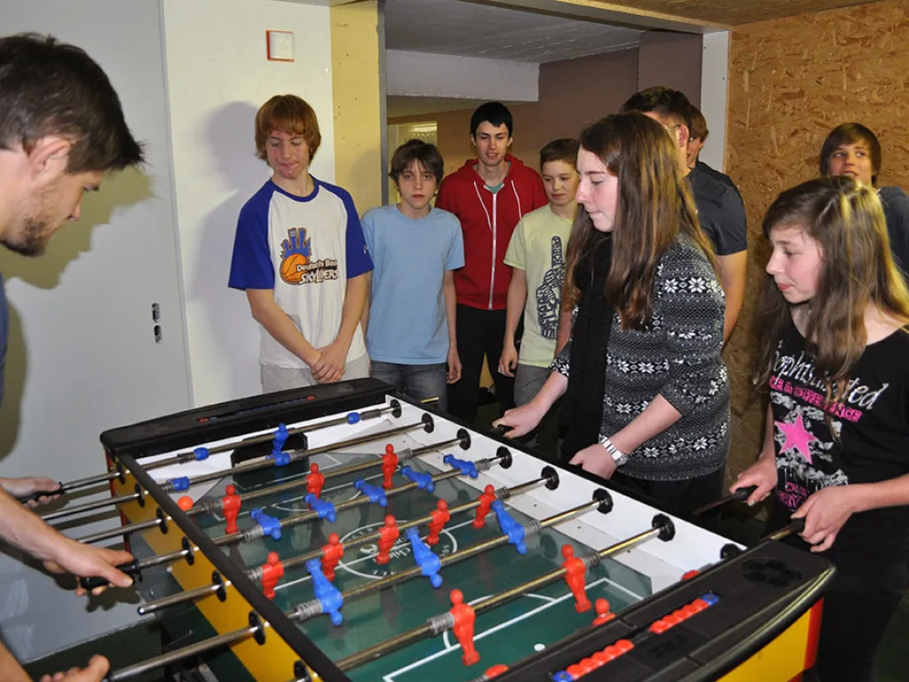 Jugendliche spielen im Aufenthaltsraum Tischfußball.